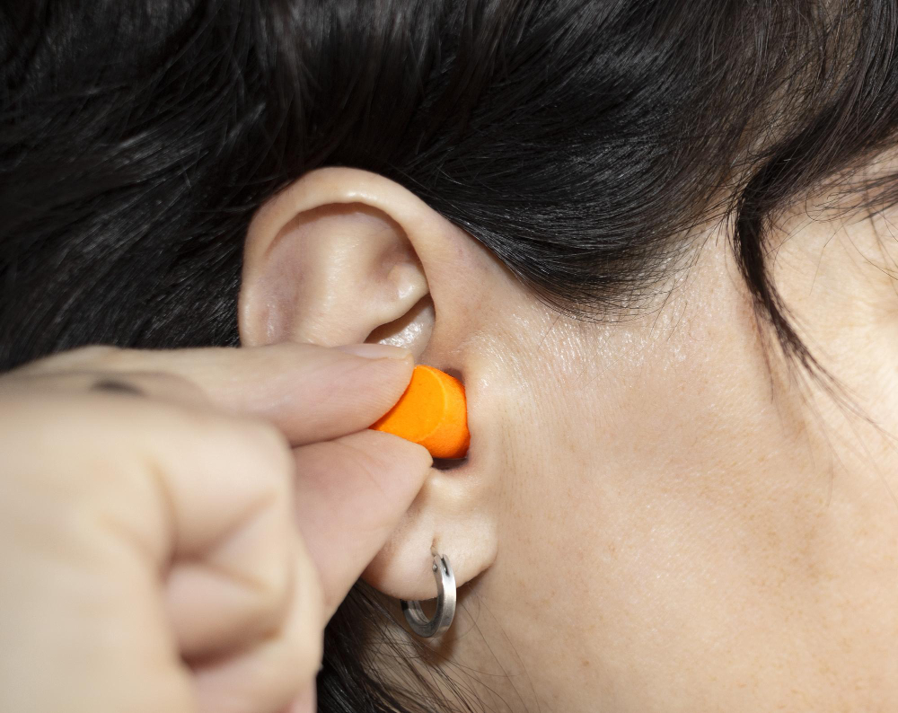 woman inserts orange silicone plug her ear avoid annoying noises 1 slaapoordoppen