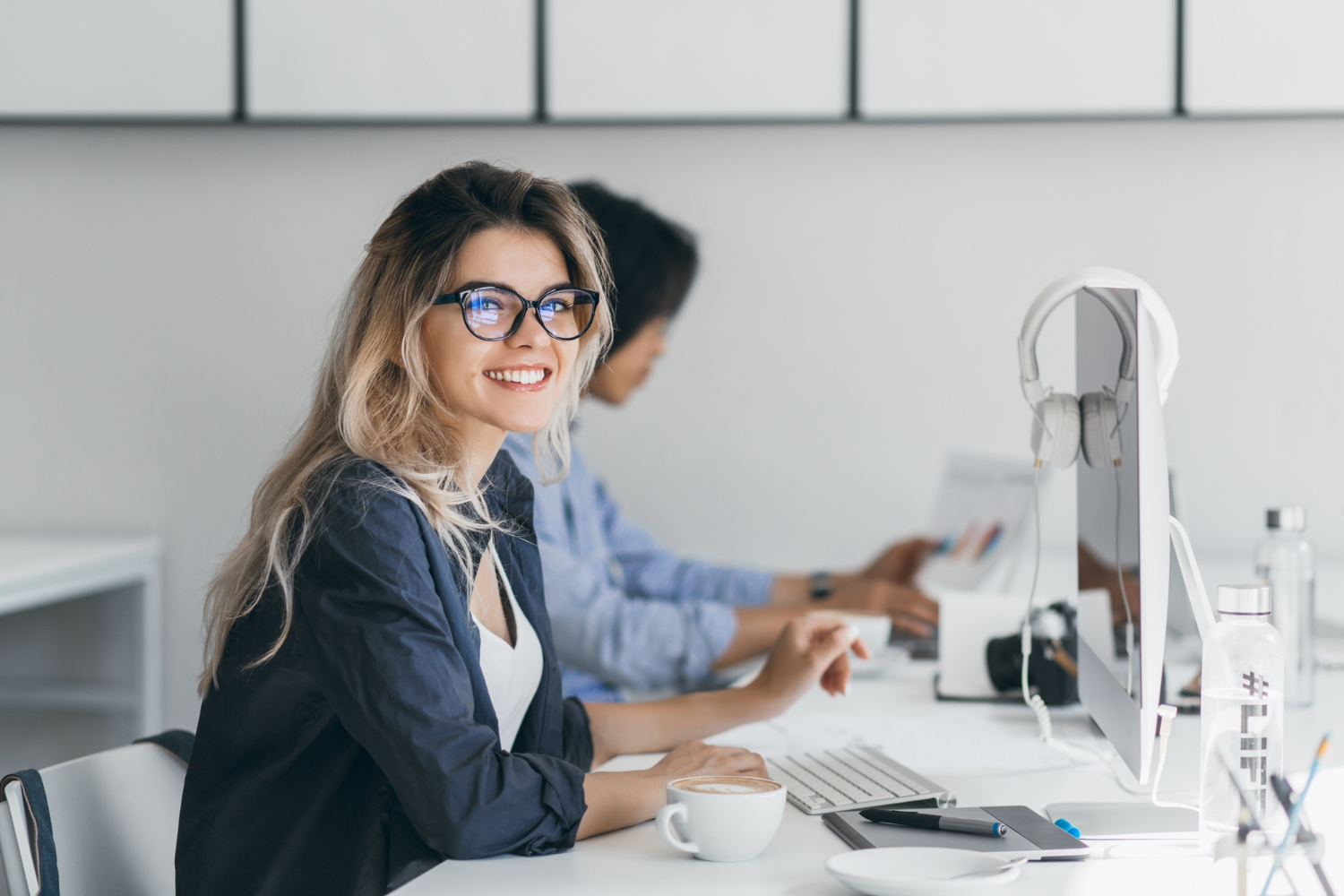 attractive laughing freelancer woman posing with cup coffee her workplace chinese student blue shirt works with document campus with blonde friend glasses blauw licht filter bril vrouwen
